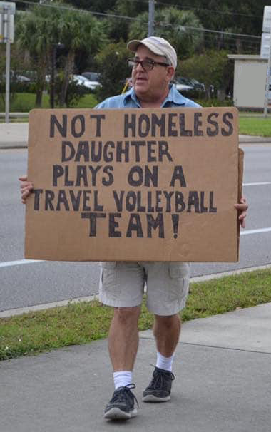 Man Standing Along Road Holding Sign